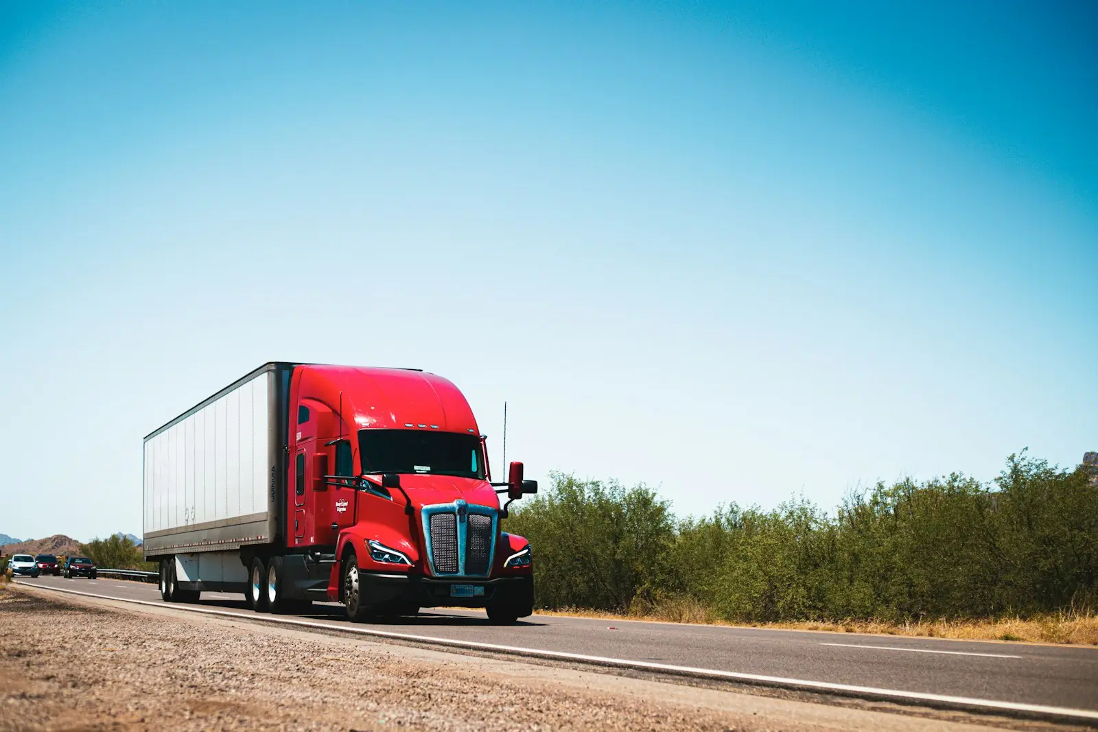 Red semi-trailer truck driving along an open highway