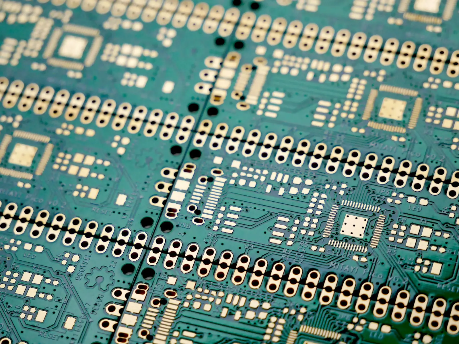 Close-up of a green printed circuit board with rows of component pads