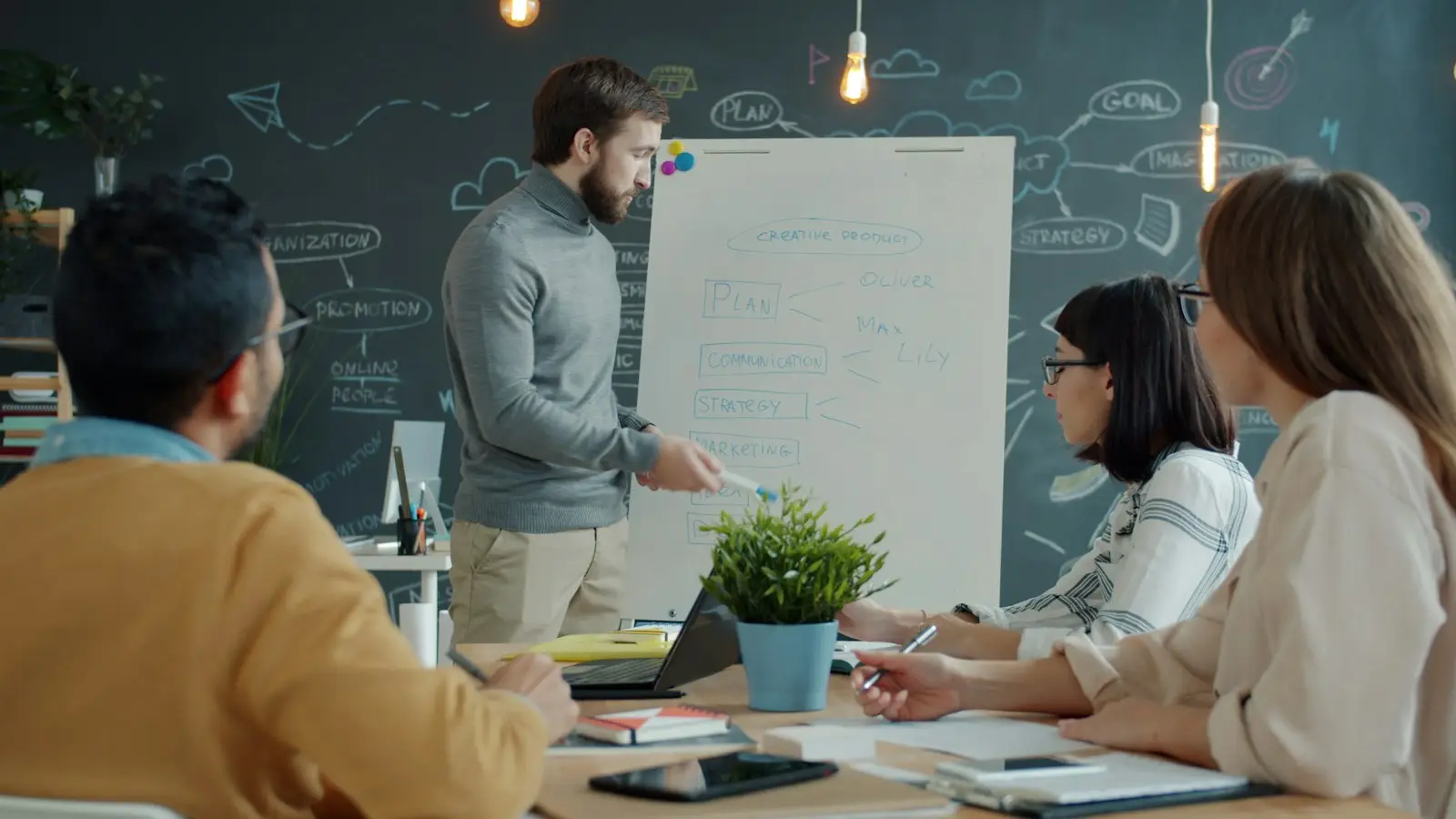 A small team discussing a plan around a whiteboard in a workshop